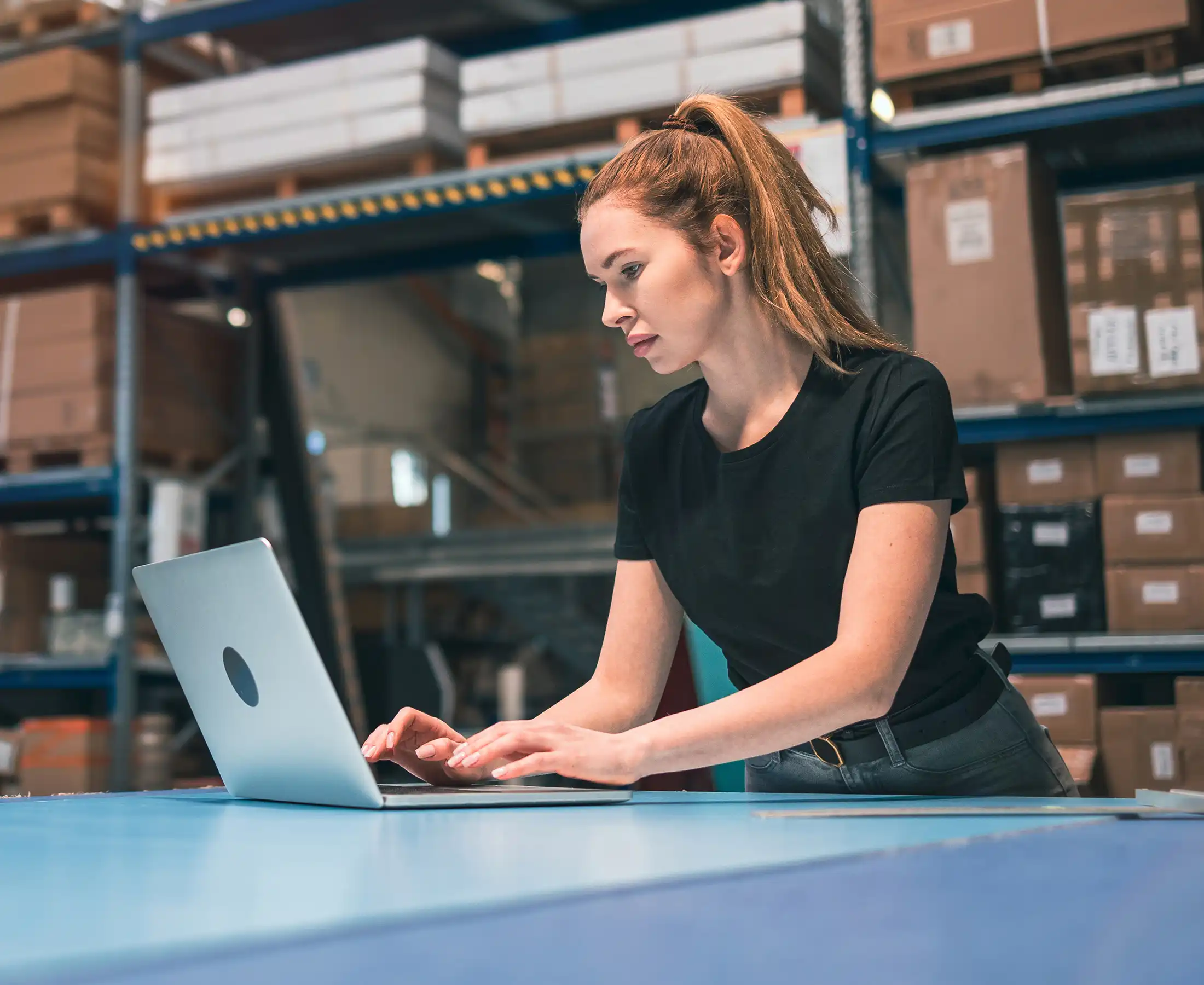 Woman using laptop at warehouse